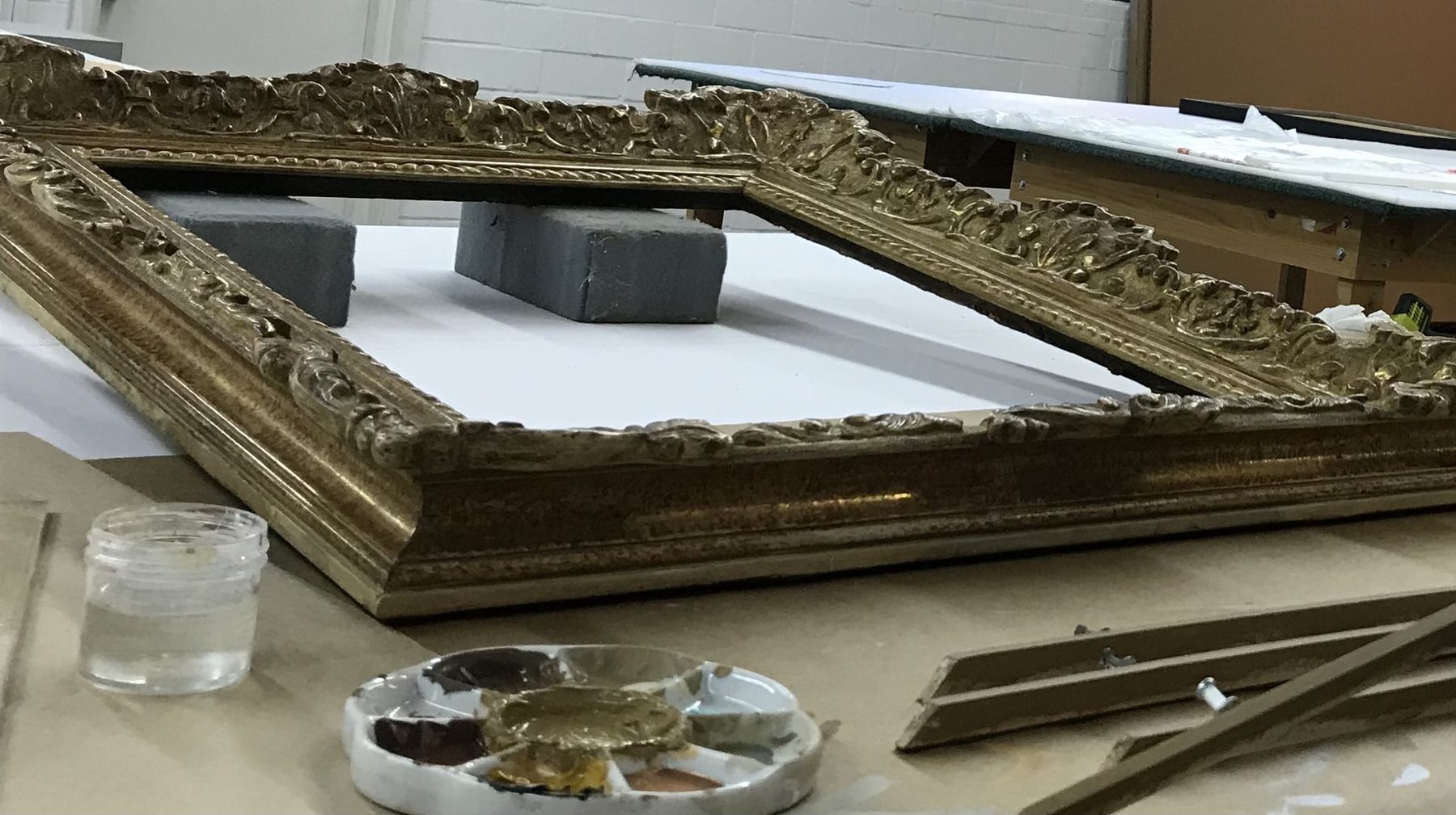 Antique carved gilt frame on the SBAS restoration bench with pigments and gilding tools