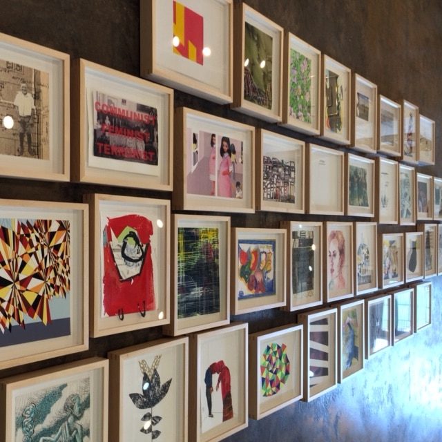 Densely hung gallery wall of framed works on paper in a private collection, framing by SBAS Houston
