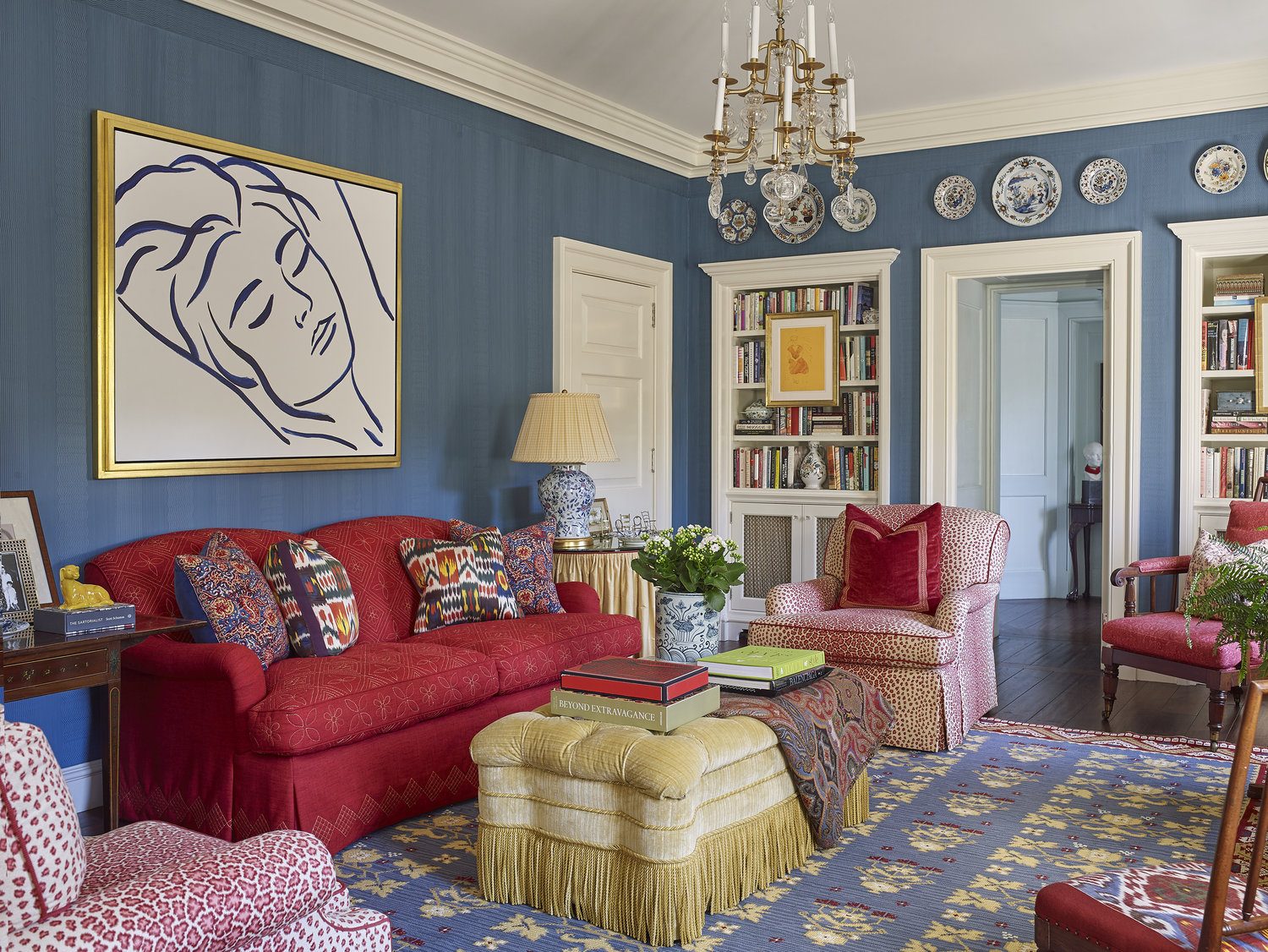 Family room with a framed Matisse line drawing above a red sofa, framing by SBAS Houston