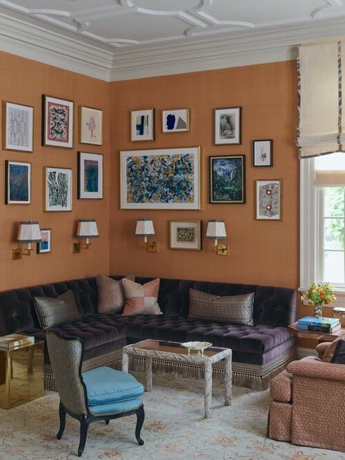 Terracotta salon wall densely hung with framed works, framing by SBAS Houston